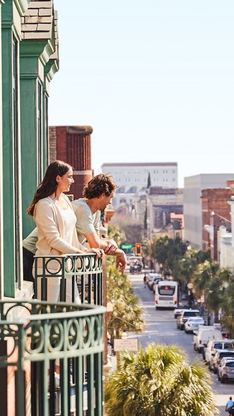 A couple standing on the balcony and overlooking the Historic District of Charleston South Carolina
